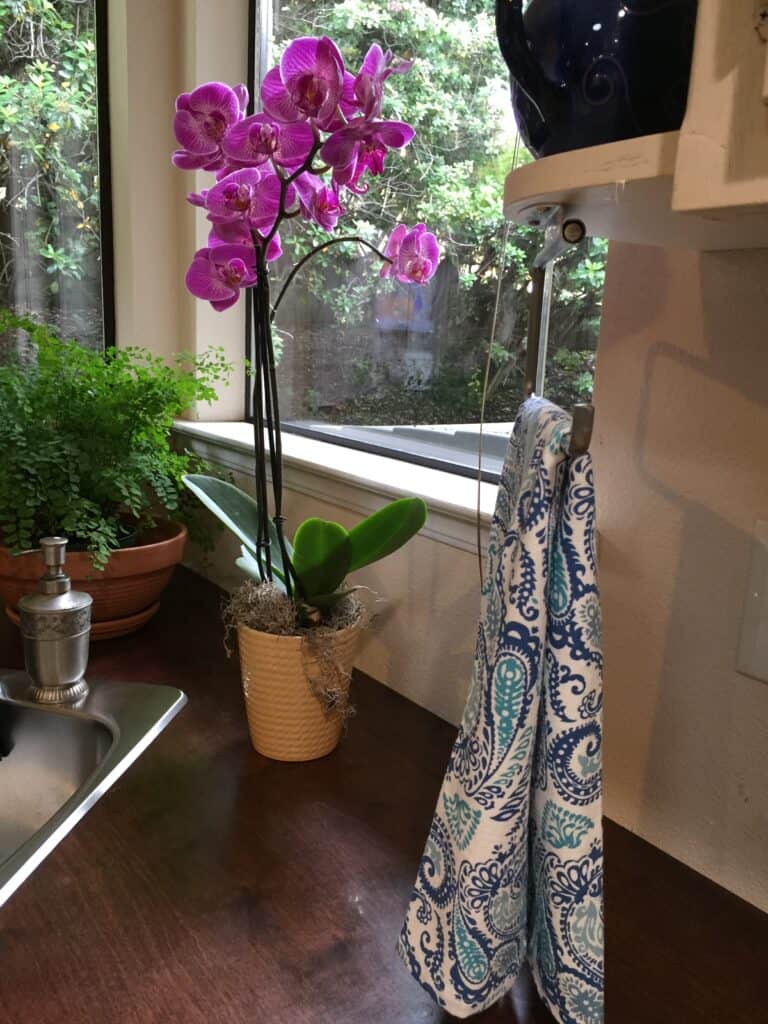 A cloth towel hanging on a paper towel rack near the kitchen sink.