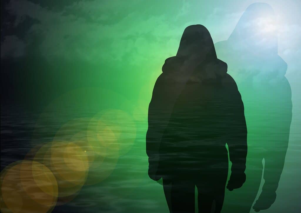 Silhouette of a person standing in front of a bright green ocean at night.  A shadow is emitting out from the right side of the person.  Mournful.
